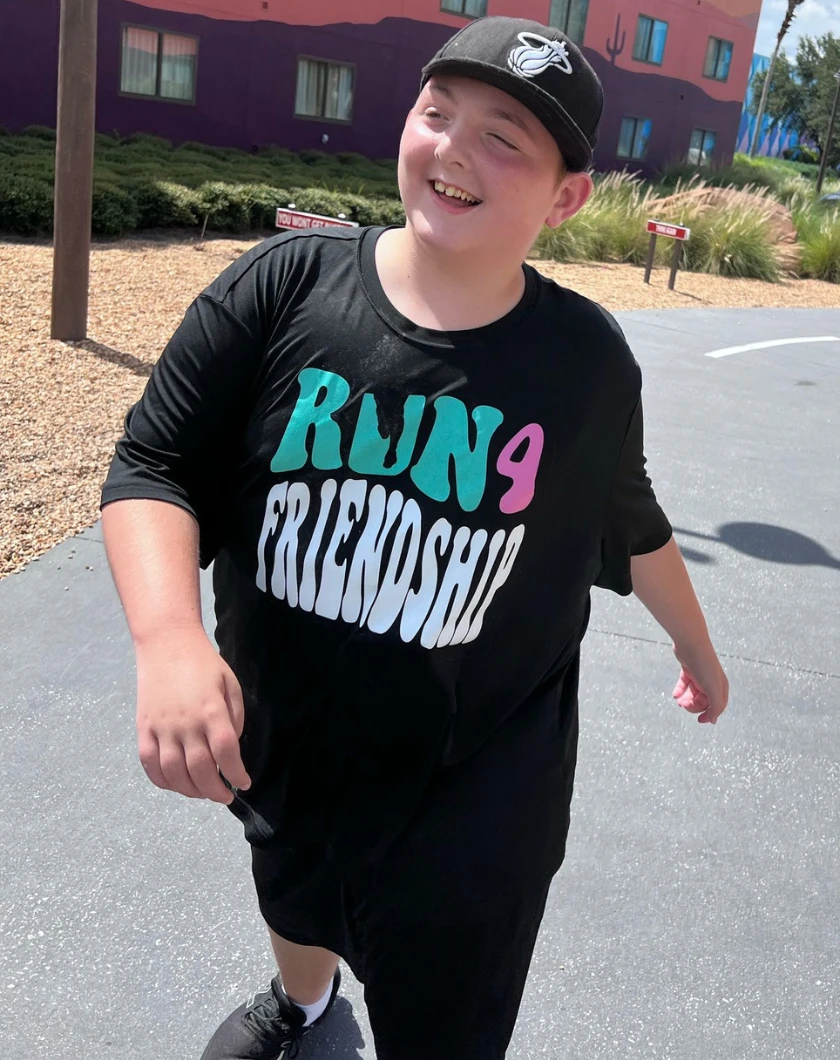 mark wearing a black t-shirt and cap, strutting down the sidewalk.