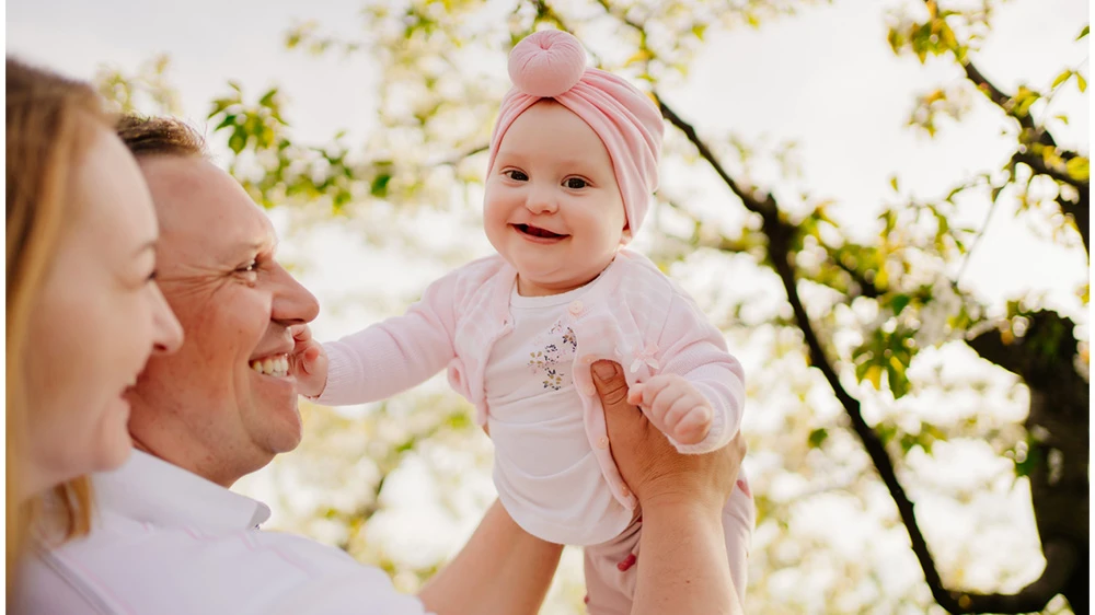 parents holding up their smiling baby girl.