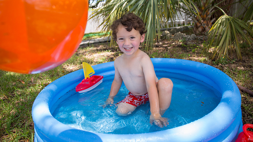 boy playing in an inflatable pool.