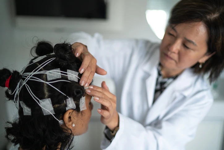 doctor placing electrodes on girl's head.