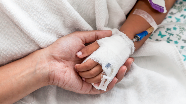 parent holding the bandaged hand of child patient.