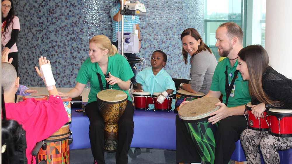 music therapists play the drums with patients and family.