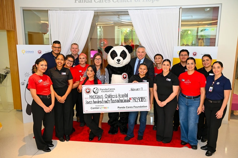 Group photo with check in front of Panda Cares Center of Hope.