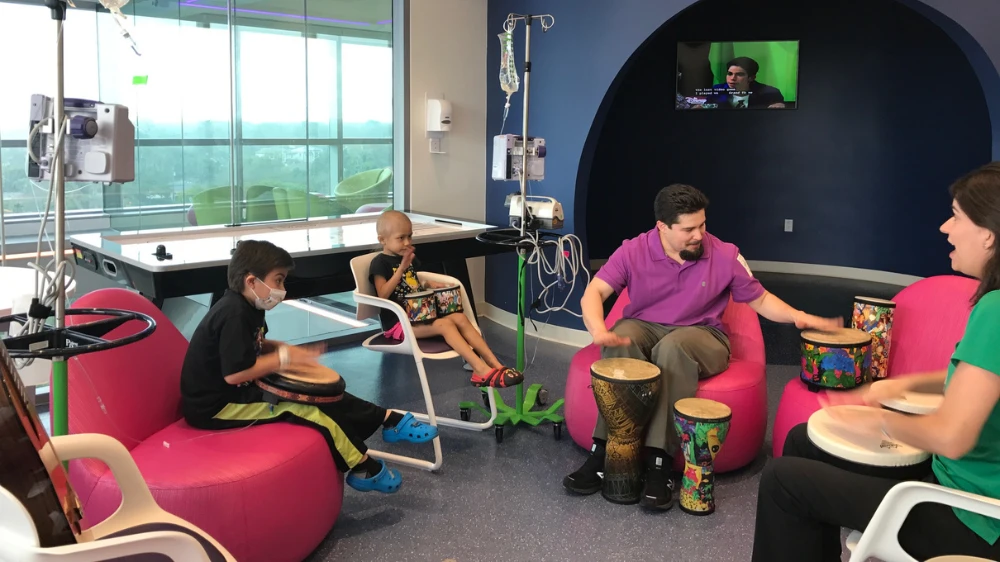 music therapists play the drums with patients and family.