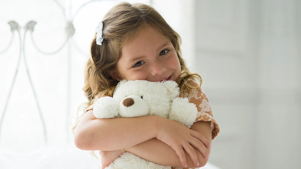girl hugging white teddy bear.