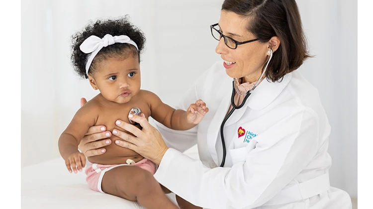female doctor checking heart of baby girl with stethoscope.