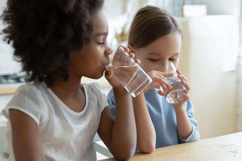 Two young girls drinking water.