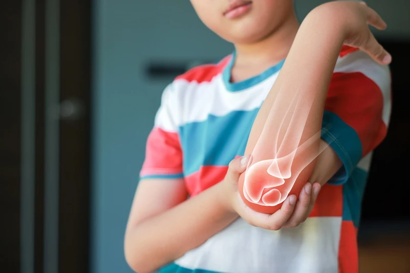 Boy holding elbow in pain.