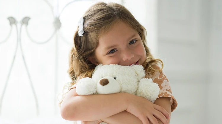 girl hugging white teddy bear.
