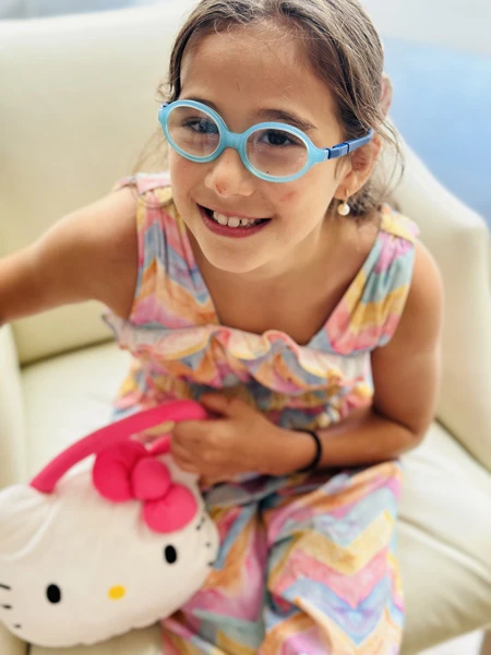 portrait of a smiling victoria in colorful dress and blue glasses.
