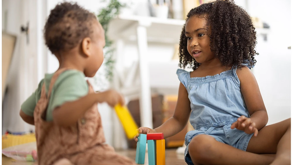 two children playing with colored wooden blocks.