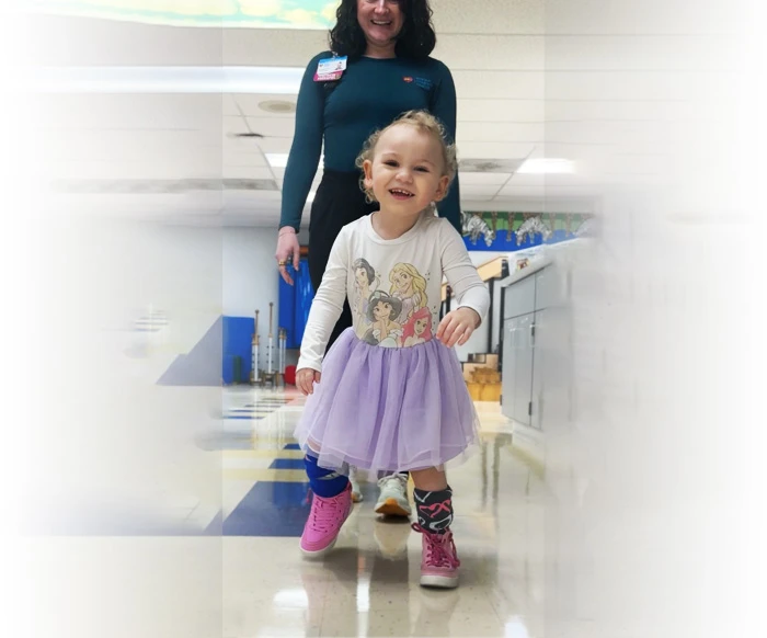 Lily takes some steps forward with the help of her physical therapist.