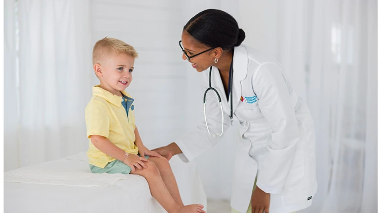 female doctor smiling at boy sitting on exam table.