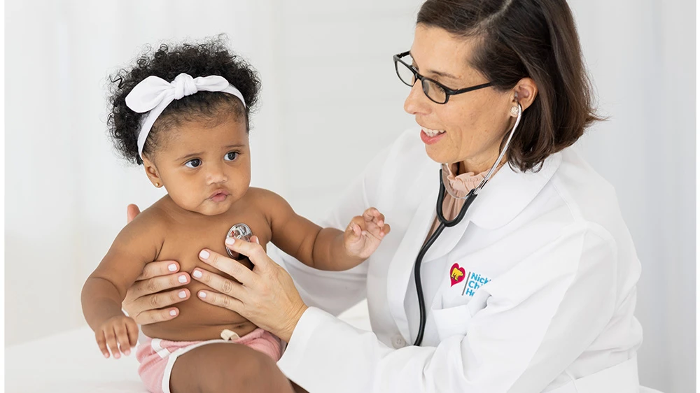 female doctor checking heart of baby girl with stethoscope.