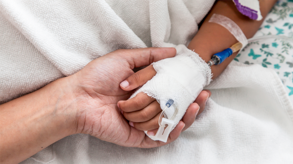 parent holding the bandaged hand of child patient.
