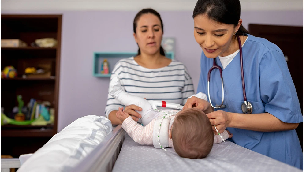 orthopedic nurse placing a hip brace on baby.