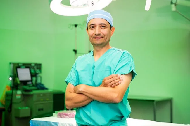 Dr. Jaime A. Gomez in surgical suite in green scrubs.