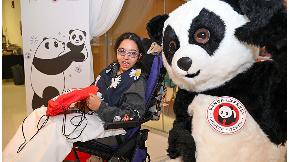 panda mascot and girl in wheelchair smiling.