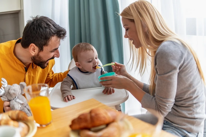 parents feeding baby boy solids.