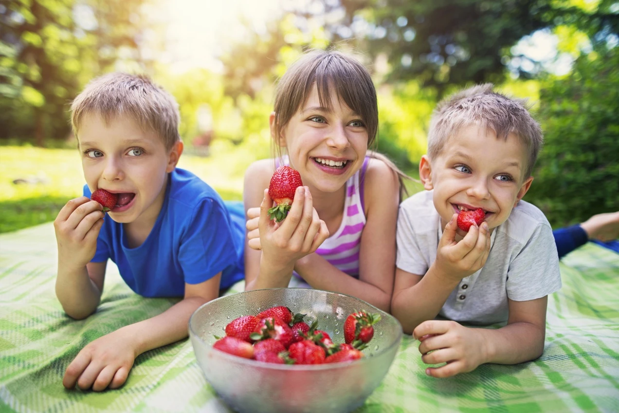 three kids eating strawberries.