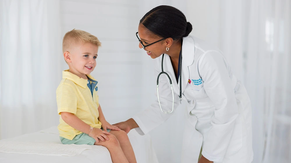 female doctor smiling at boy sitting on exam table.