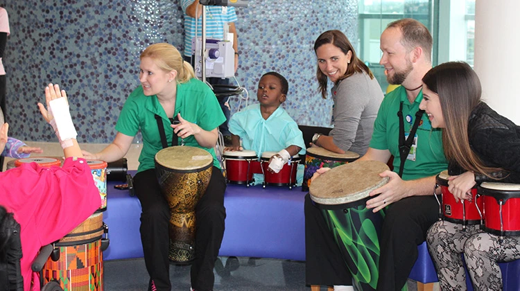 music therapists play the drums with patients and family.